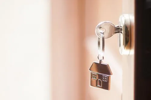 Close-up of a house-shaped keychain hanging on a door knob.